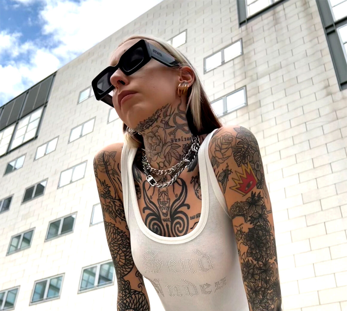 Confident bearded male with tattoo in sunglasses wearing stylish outfit  looking away while standing on street with modern buildings in city   hipster unshaven  Stock Photo  528089142